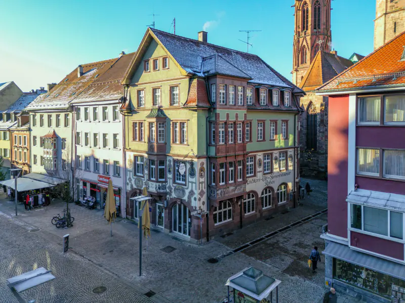 Historisches Eckhaus mit zwei Erkern, dahinter der Münsterturm